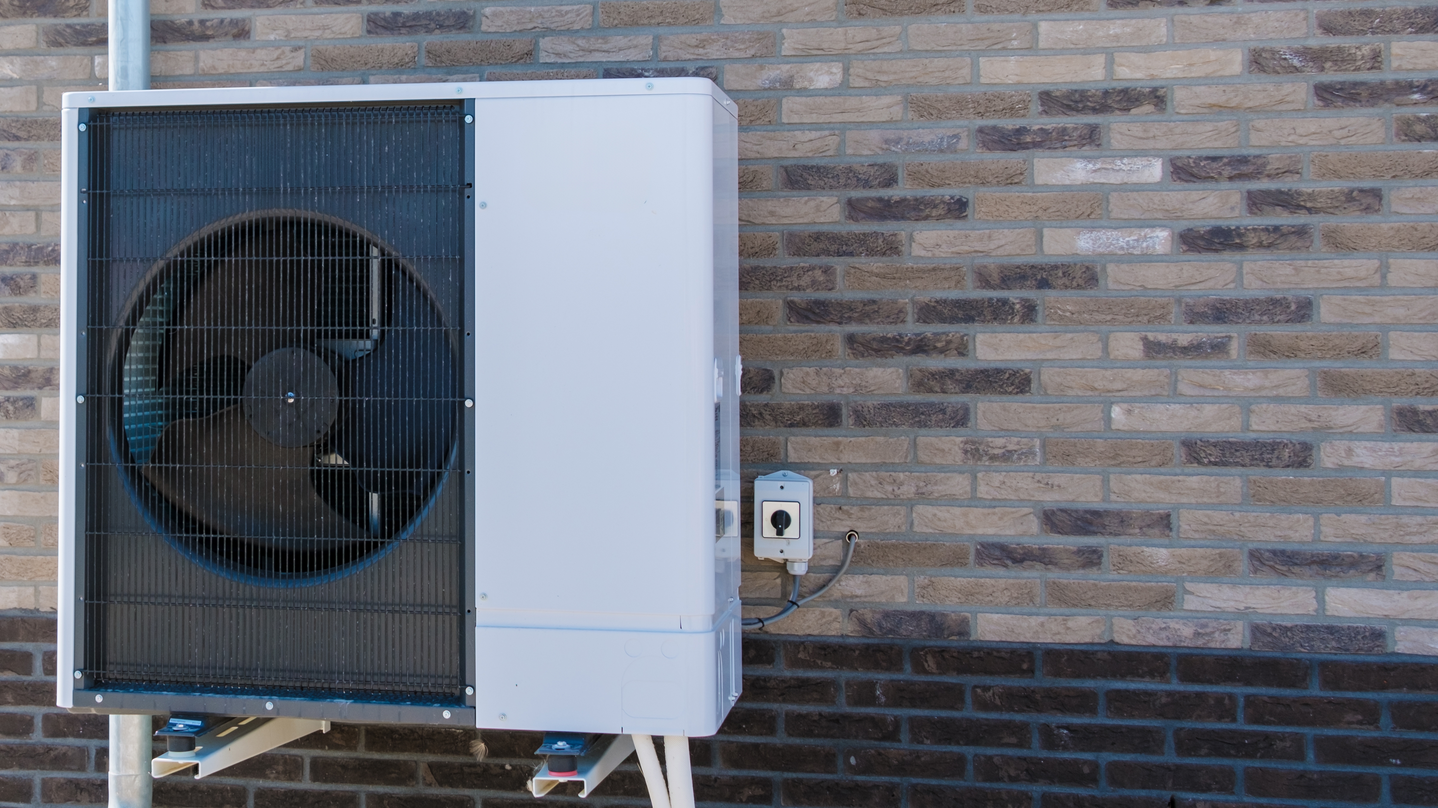 An,Air,Source,Heat,Pump,Is,Mounted,On,A,Brick
