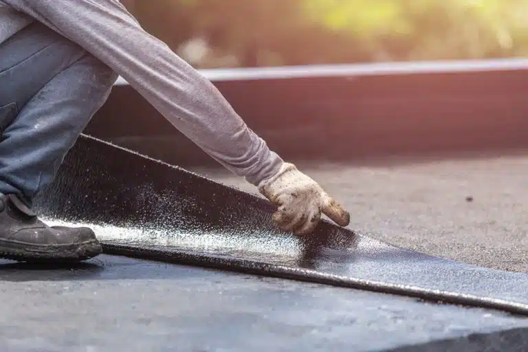 Asia,Worker,Installing,Tar,Foil,On,The,Rooftop,Of,Building. 7 Common Types of Roofs for Commercial Buildings