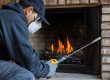 a professional conducting a chimney cleaning with a gas fireplace inside a home